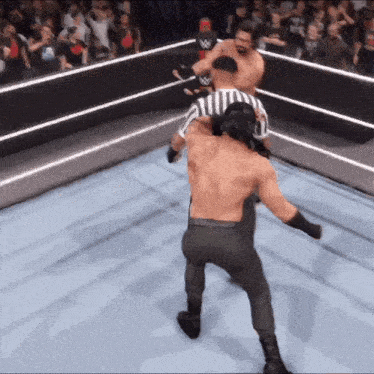 a referee in a wrestling ring with a w logo on the back of his shirt