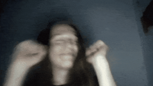 a blurry picture of a woman 's face with her hands in the air