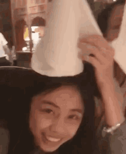 a woman is holding a piece of paper on her head .