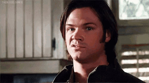 a man with long hair is making a funny face while looking at the camera .