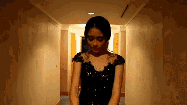 a woman in a black dress is standing in a hallway .