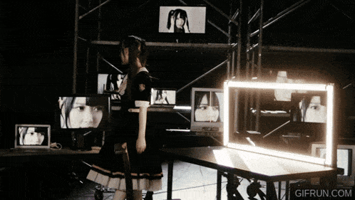 a woman in a black dress stands in front of a wall of monitors with gifrun.com written on the bottom right