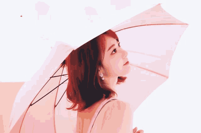 a woman with red hair is holding a pink umbrella in her hand .