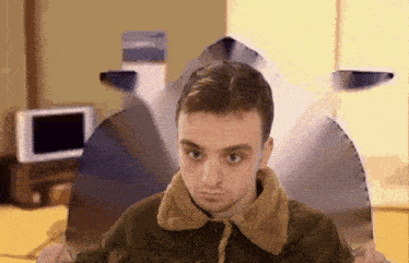 a man wearing a jacket with a furry collar looks at something