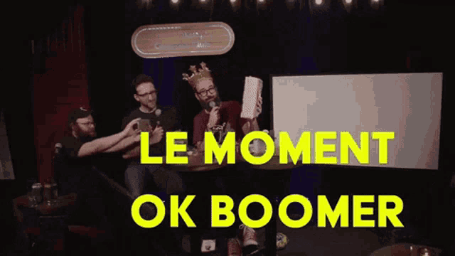 a man with a crown on his head is holding a piece of paper with the words le moment ok boomer written above him