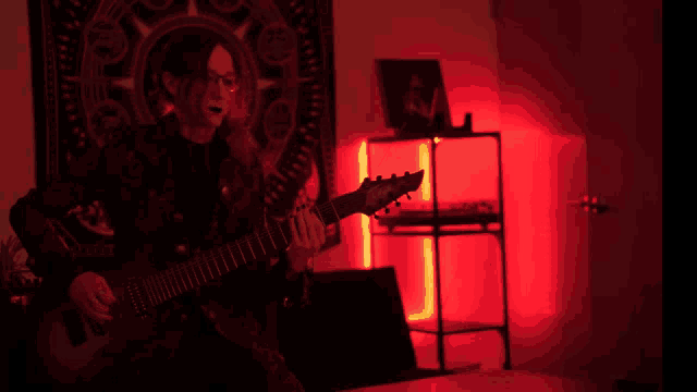 a person playing a guitar in a dark room with red lights