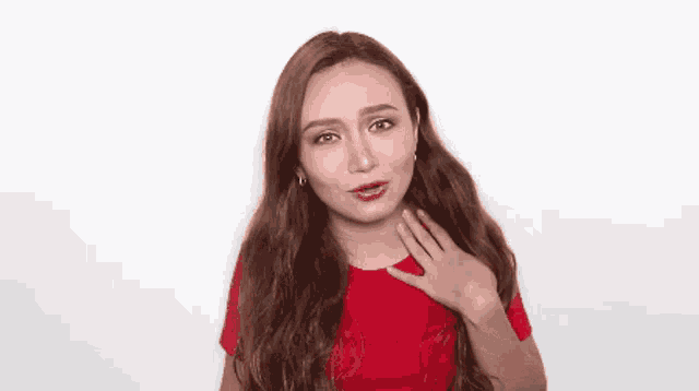 a woman in a red shirt is touching her chest