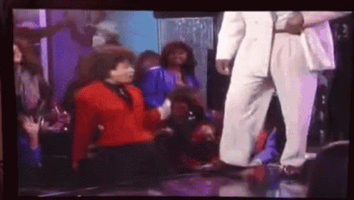 a man in a white suit is dancing with a woman in a red shirt
