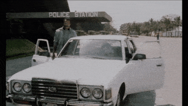 a white car is parked in front of a building that says police station
