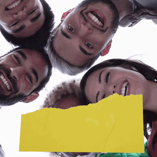 a group of people are smiling with a yellow piece of paper in front of them