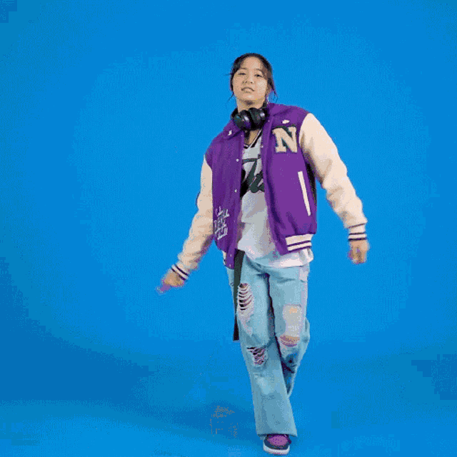 a woman wearing headphones and a jets shirt is dancing