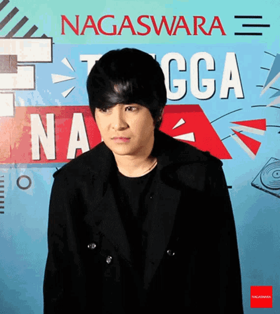 a young man stands in front of a sign that says nagaswara