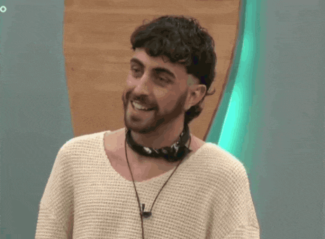 a man with curly hair and a beard wearing a white sweater and headphones .