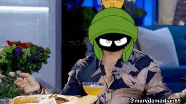 a man wearing a mask of marvin the martian holds a glass of orange juice