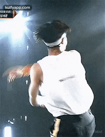 a man in a white tank top is dancing on stage .