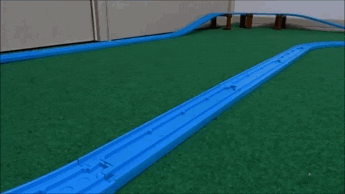 a toy train is going down a track with a bunch of boxes on the tracks .