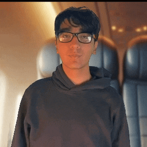 a young man wearing glasses and a black hoodie stands in front of a plane
