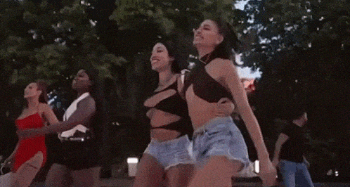 a group of women are dancing in a park while holding hands .