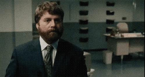 a man with a beard in a suit and tie is standing in an office .