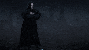 a woman in a black cape is standing in front of a dark building