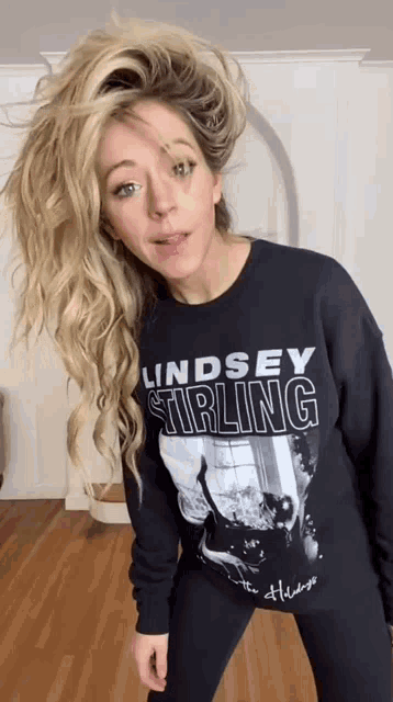 a woman wearing a lindsey stirling sweatshirt is dancing