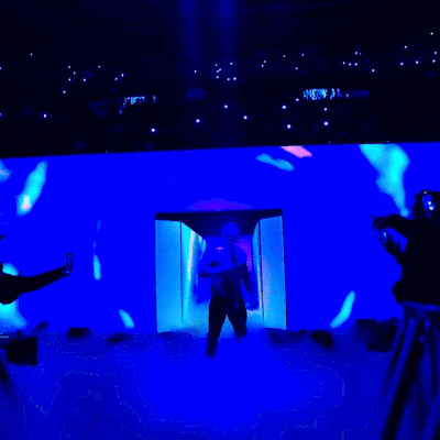 a man is standing in front of a stage with a purple light behind him