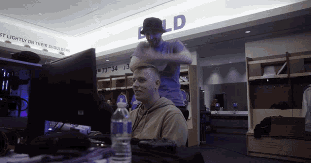 a man sitting in front of a computer in a locker room with the word bold on the ceiling