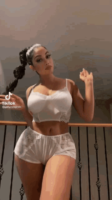 a woman in a white bra and shorts is standing on a railing .