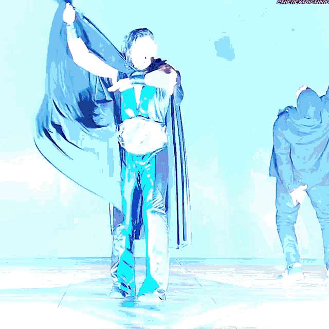 a man in a cape holds a belt that says ' the next thing ' on the bottom