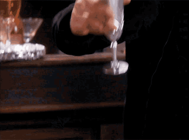 a man in a black shirt is holding a wine glass in his hand