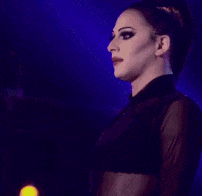 a woman in a black outfit is standing in front of purple lights