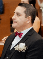 a man in a suit with a red bow tie is sitting in a church .