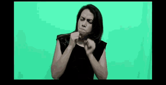 a woman in a black dress is standing in front of a green screen .