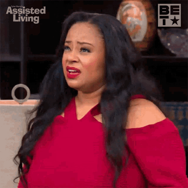 a woman in a red dress is making a funny face on a television show called assisted living .
