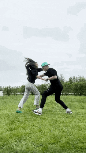 a man and a woman are standing in a grassy field .