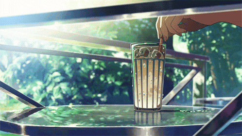 a person is pouring a drink into a glass on a table