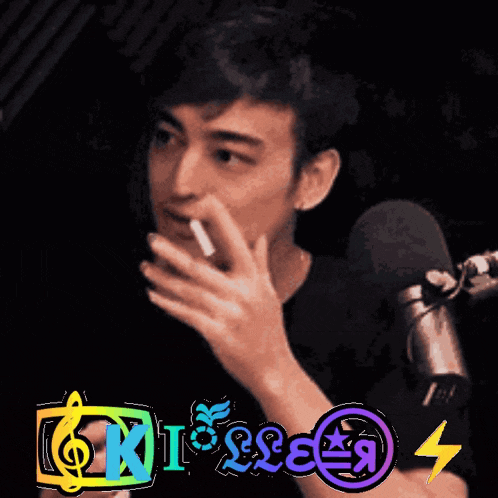 a man is smoking a cigarette in front of a microphone and the words kisses are visible