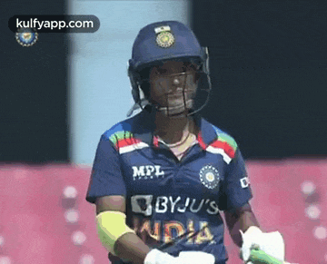 a female cricket player wearing a helmet and a blue shirt is holding a bat .