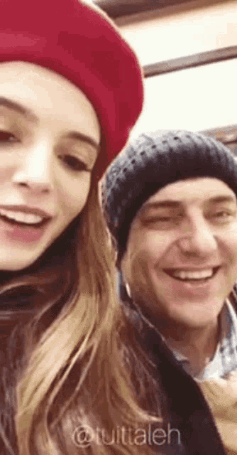 a woman wearing a red beret is smiling next to a man wearing a black hat ..