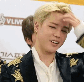 a man in a suit is scratching his forehead .