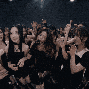 a group of young women are dancing in a dark room