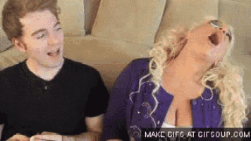 a man and a woman are sitting on a couch and laughing .