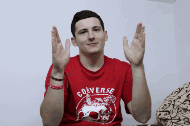 a man wearing a red converse t-shirt with a skull on it