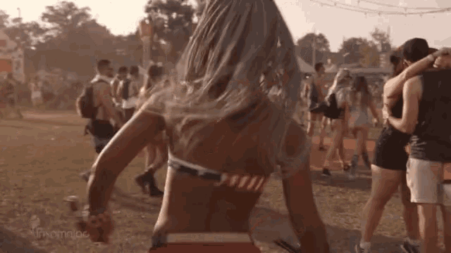 a woman in a bikini is dancing in a crowd at a festival .