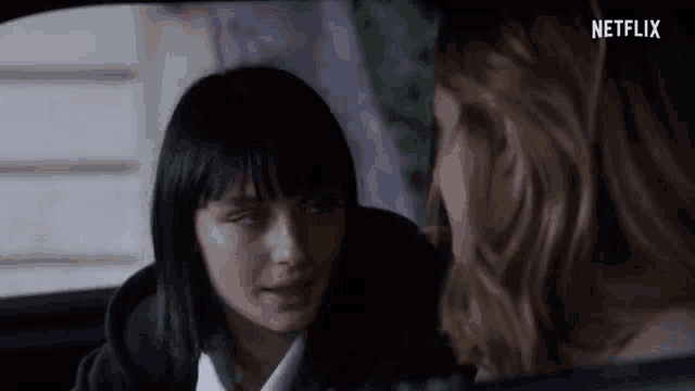 a woman is sitting in the back seat of a car talking to another woman .