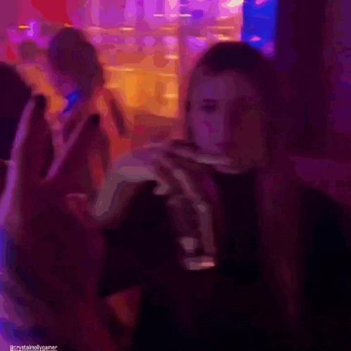 a woman with long hair is holding a glass of wine in a dark room