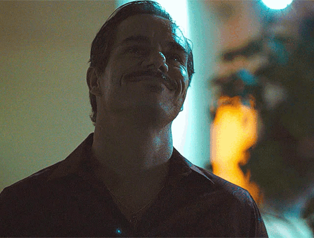 a man with a mustache is smiling and looking up at something