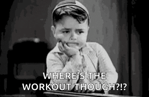 a little boy is sitting at a desk with his hand on his chin and asking where 's the workout though .