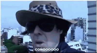 a woman wearing a cowboy hat and sunglasses is standing in front of a city .