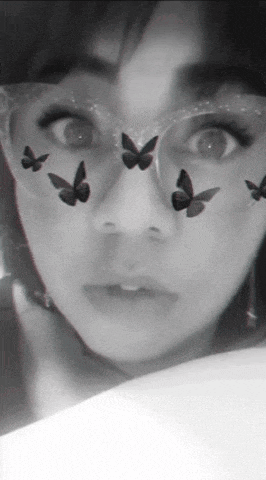 a black and white photo of a woman 's face with butterflies on her face .